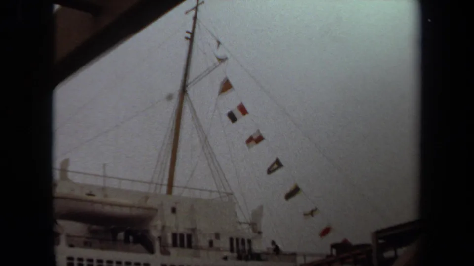 Faded 1971 Long Beach 8mm frame showing the cruise ship mast, hanging signal flags, deck windows, and part of the pier gangway.