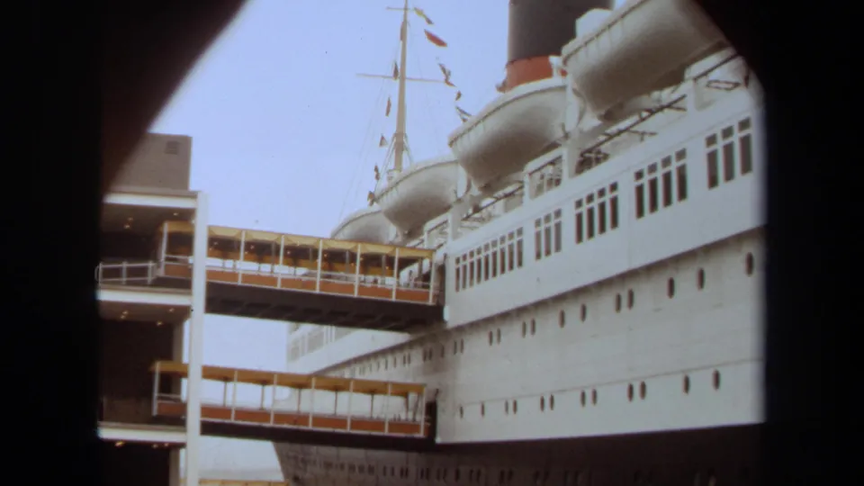 The docked ocean liner remains framed by dark foreground edges, with terminal gangways crossing to the vessel.