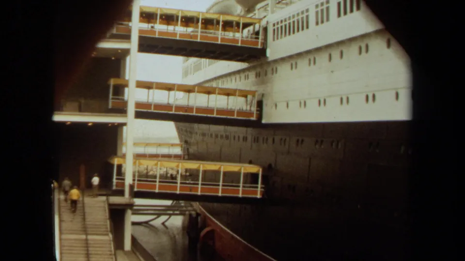 1971 8mm frame showing passengers boarding a large ship at Long Beach through several stacked gangways.
