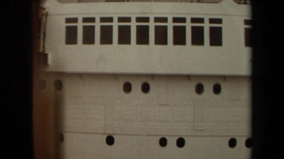 Close 1971 Long Beach home-movie view of a ship's white side, showing rectangular windows, portholes, and textured hull panels.