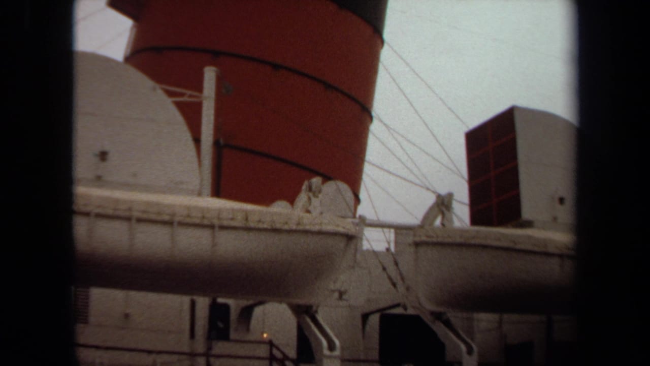 1971 Long Beach home-movie frame showing an ocean liner's port side, lifeboat, radar dome, rigging, and red-and-black funnel.