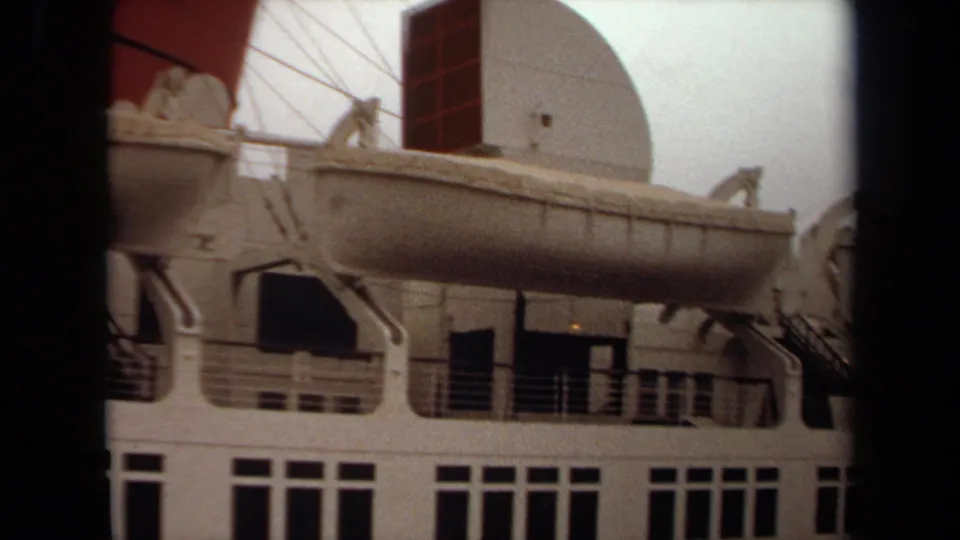 1971 Long Beach frame showing a close port-side view of lifeboat equipment, railings, deck openings, and the white radar dome.