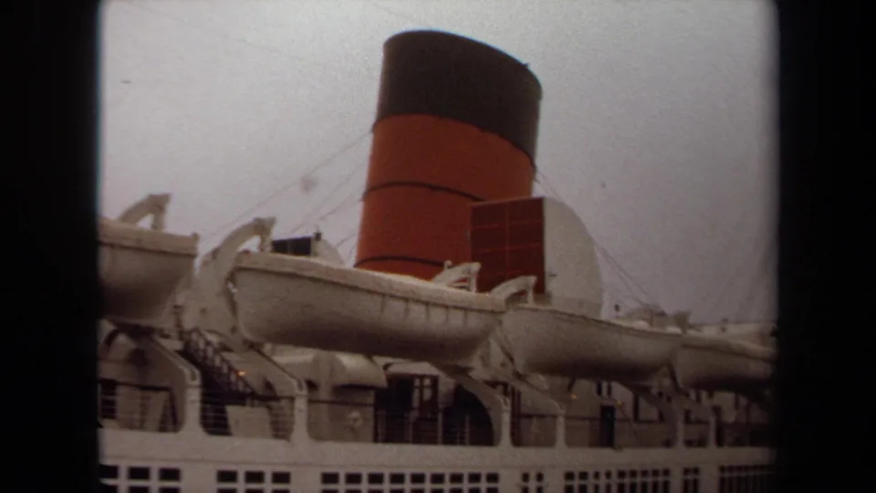 1971 Long Beach home-movie frame of a large passenger ship with lifeboats along the deck and the red-and-black funnel behind them.