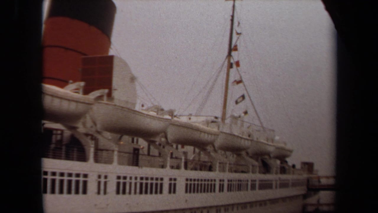1971 Long Beach home-movie view of a docked white passenger ship with lifeboats, mast flags, railings, and a red-and-black funnel.