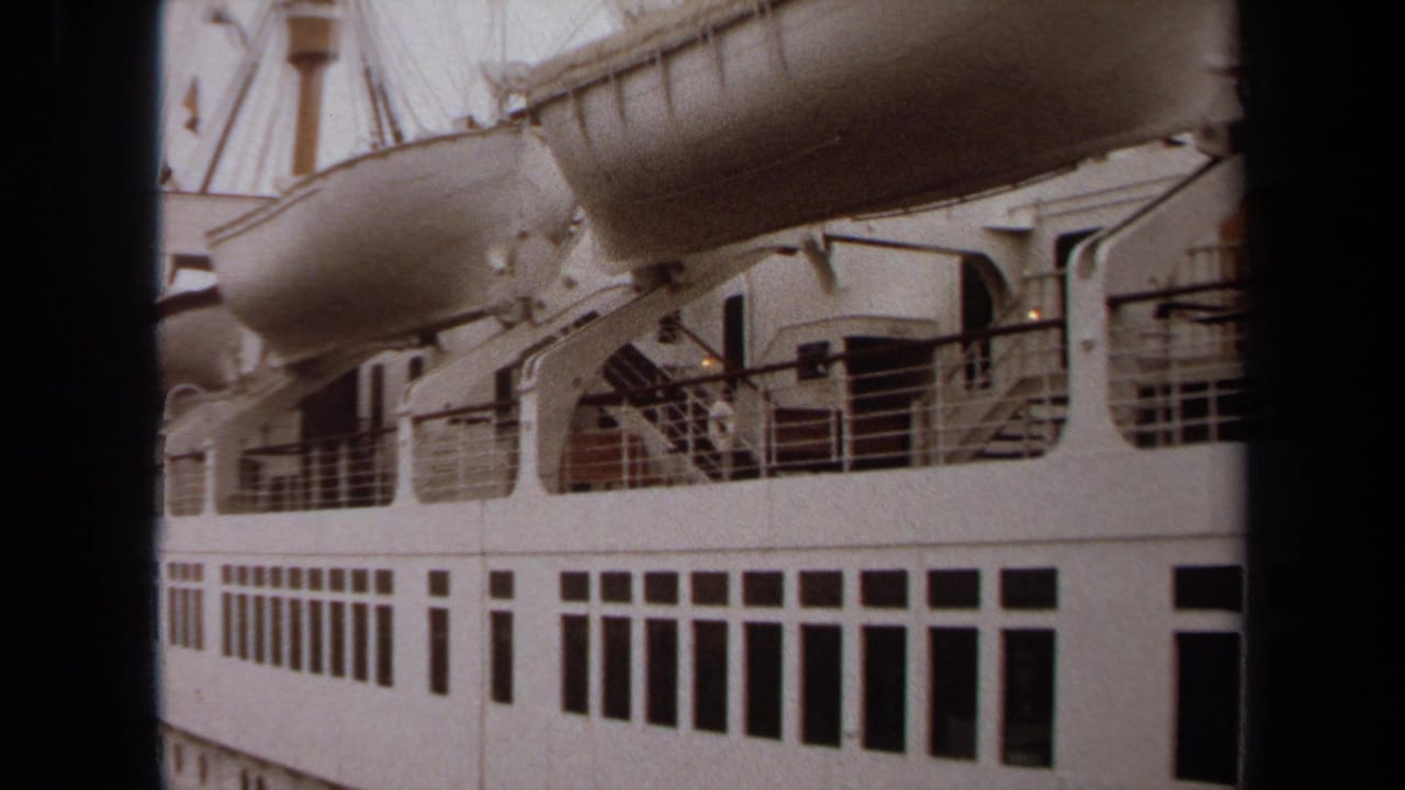 White passenger ship side with rows of windows, lifeboats, davits, and dark foreground framing.