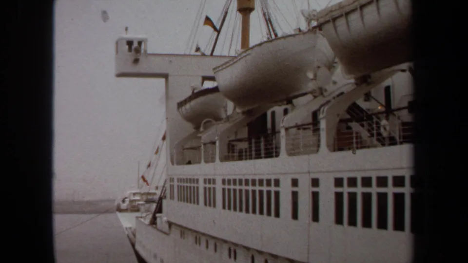 1971 Long Beach cruise-boarding footage showing the side of a white passenger ship with lifeboats, railings, and water alongside.