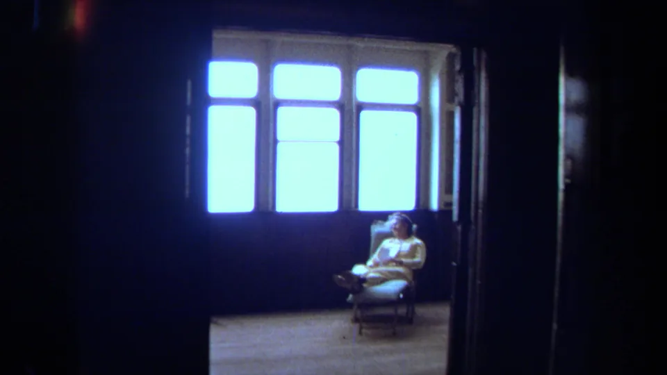 A seated passenger rests near bright windows inside the vessel, with dark doorway framing and soft 8mm exposure.