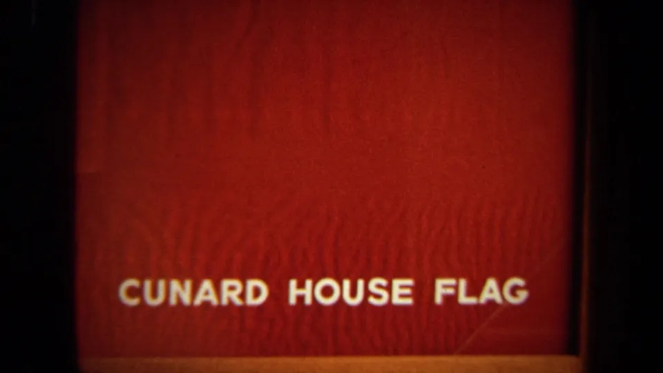 Closer soft-focus 8mm view of the red Cunard House Flag wording before the deck scene begins.
