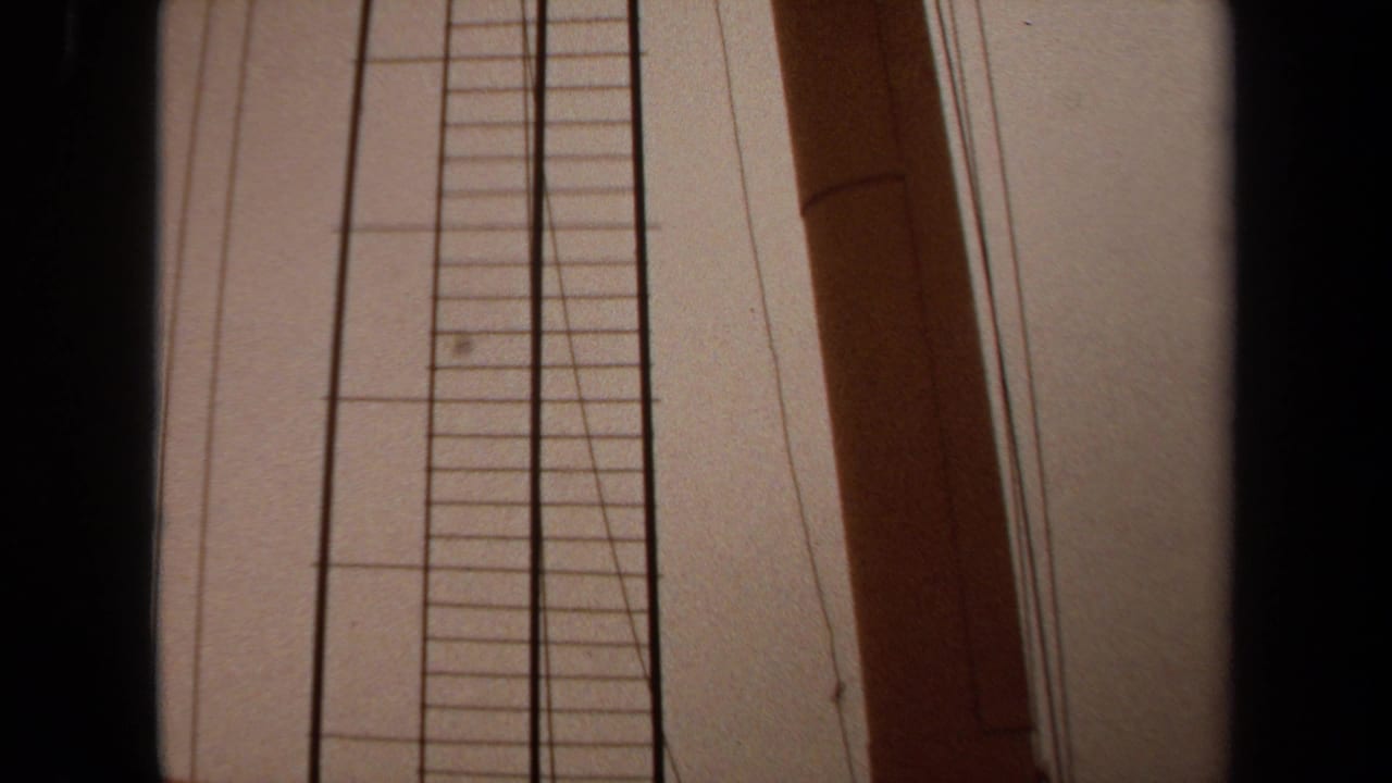 1971 Long Beach 8mm frame showing a low-angle boat-side detail with a vertical ladder, wooden mast, rigging lines, and pale sky.