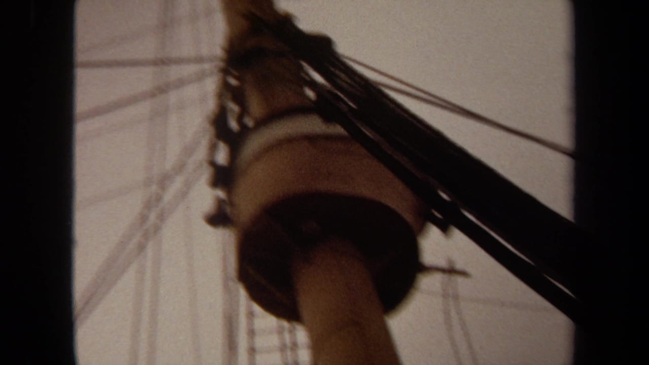 1971 Long Beach 8mm frame showing a low-angle ship mast, rigging, and dark film borders against an overcast sky.
