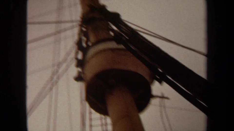 1971 Long Beach 8mm frame showing a low-angle ship mast, rigging, and dark film borders against an overcast sky.