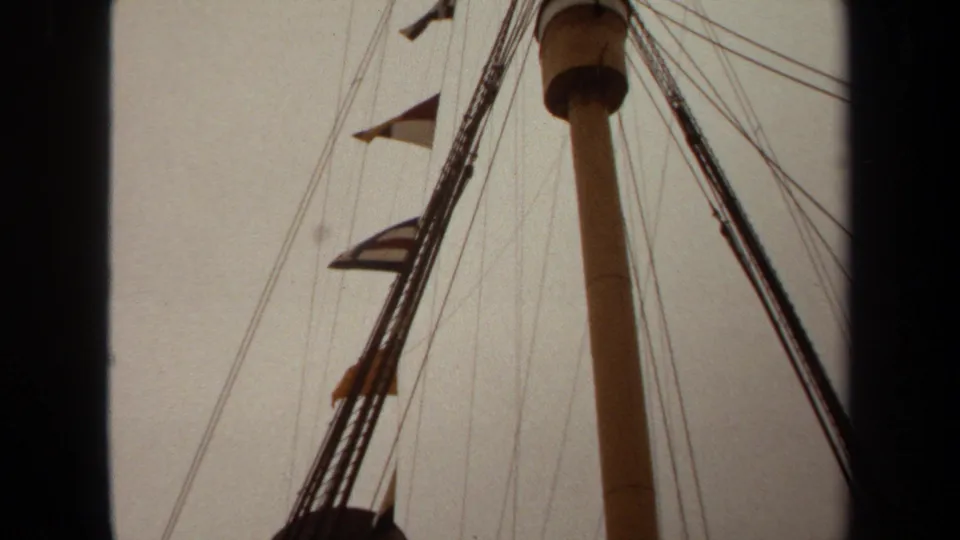 1971 Long Beach 8mm frame showing ship rigging, a vertical mast, and small signal flags from a low upward angle.