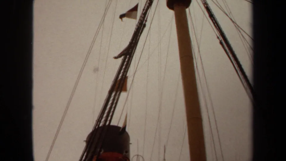 1971 Long Beach 8mm frame with mast, rigging, and several small flags visible against a muted sky.