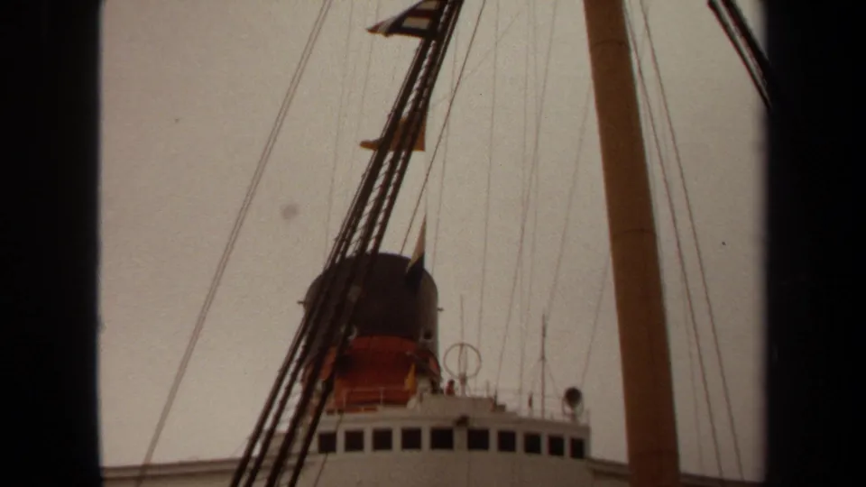 1971 Long Beach frame showing the upper deck, bridge windows, funnel, mast, rigging, flags, and antennas from below.