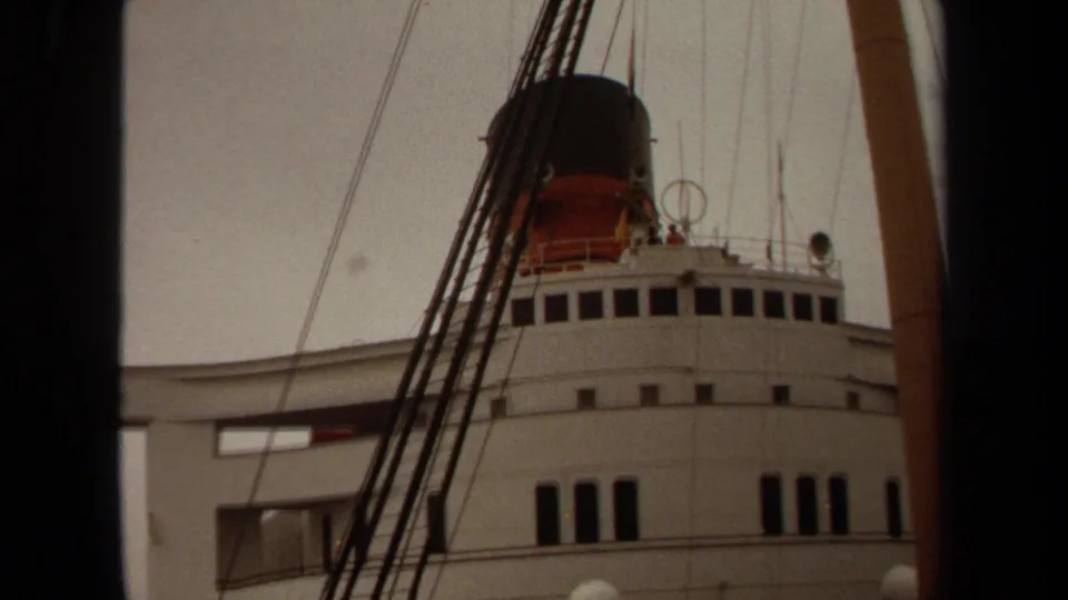 1971 Long Beach frame of a white ship superstructure, bridge windows, black-and-red funnel, mast, rigging, and railings.