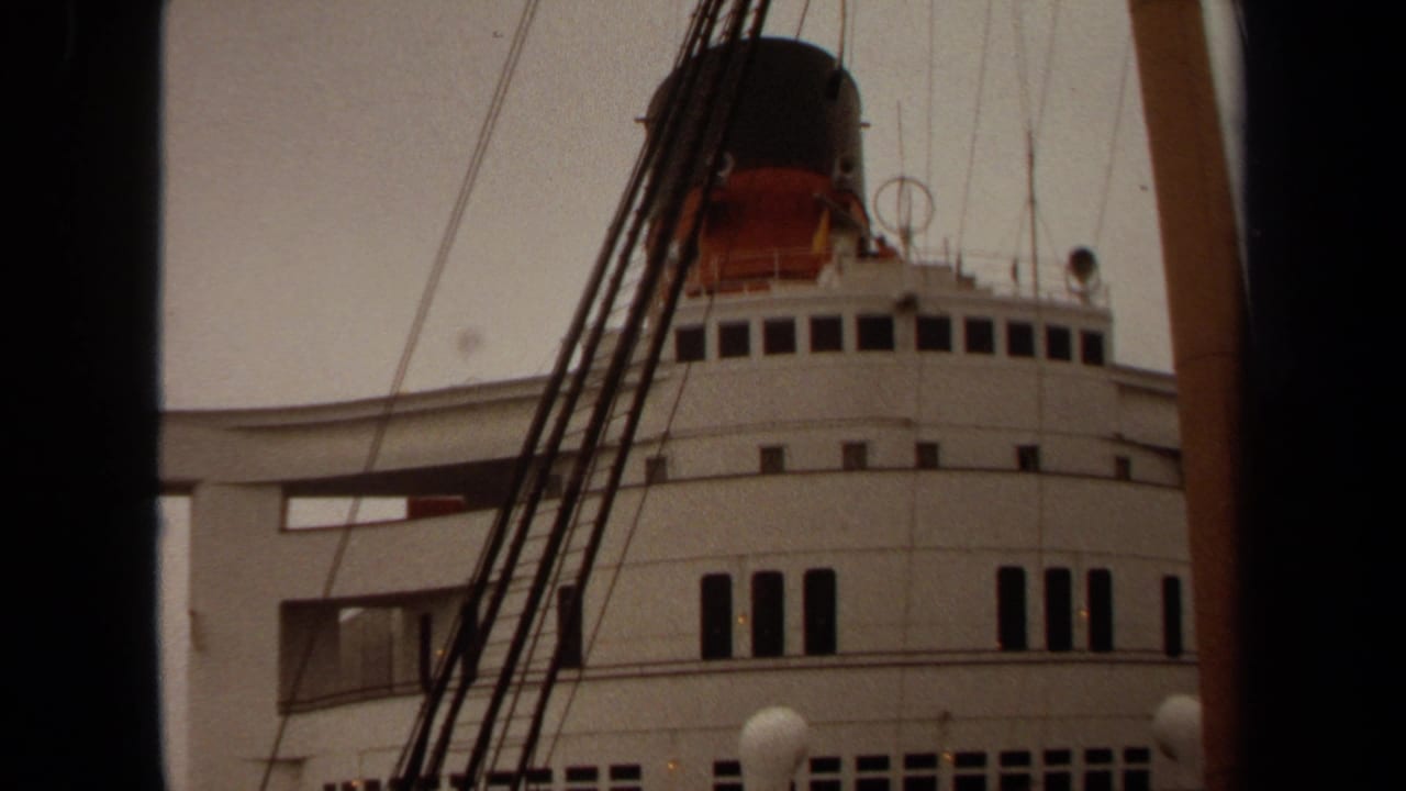 1971 Long Beach home-movie frame of a white passenger ship exterior with rows of windows, rigging, and a dark funnel above.