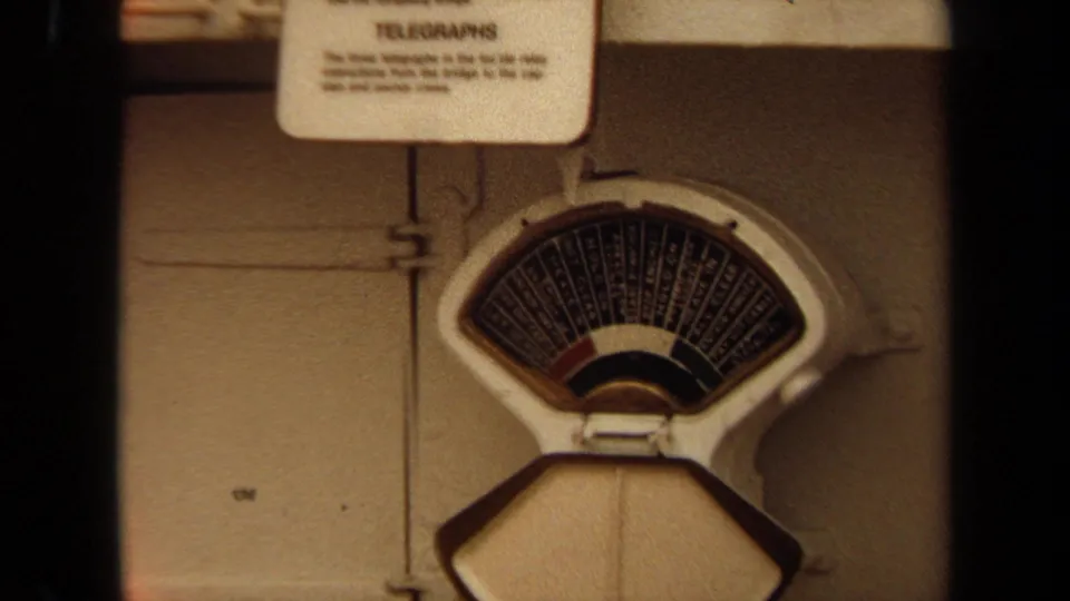 Analog shipboard gauge and posted telegraphs label appear on a white metal panel in 1971 footage.