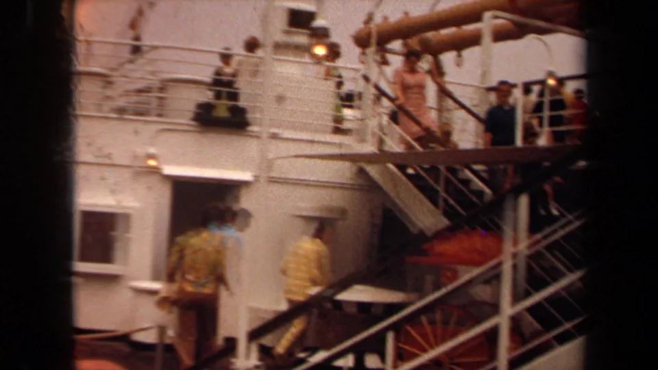 Passengers in early 1970s clothing move across a Long Beach ship deck with stairs and railings visible.