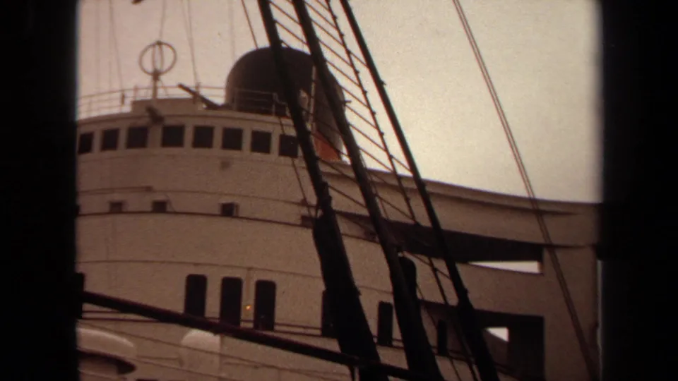 1971 8mm frame showing the passenger ship's upper decks and windows through dense foreground rigging.