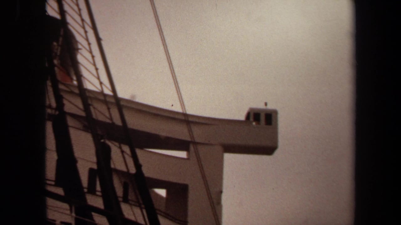 1971 Long Beach 8mm frame showing a pale elevated tower or lookout structure partly obscured by dark vertical beams and rigging.