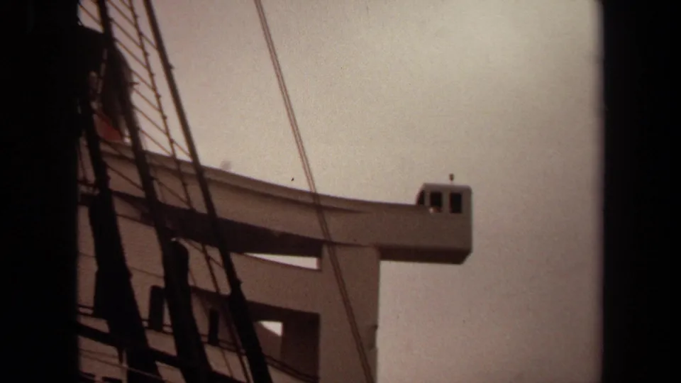 1971 Long Beach 8mm frame showing a pale elevated tower or lookout structure partly obscured by dark vertical beams and rigging.