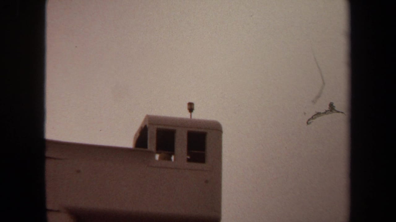 Upper section of a pale tower with two dark windows and a small antenna.