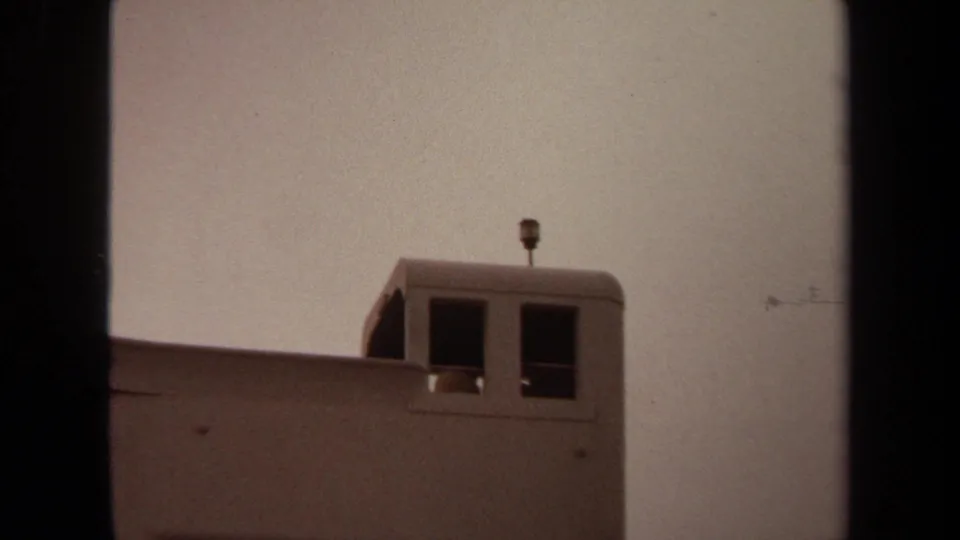 1971 Long Beach 8mm still holding on a pale tower top with dark window openings, a roof antenna, and visible film grain.