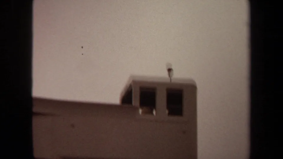 Final 1971 Long Beach frame showing the tower top, dark windows, roof antenna, and a small flag fluttering near the right edge.