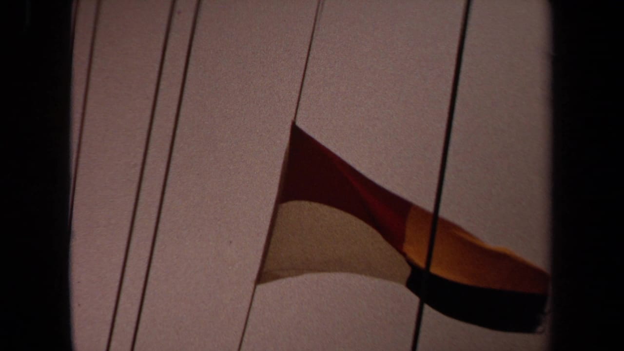 1971 Long Beach 8mm frame showing a close view of a red, yellow, and dark signal flag on ship rigging.