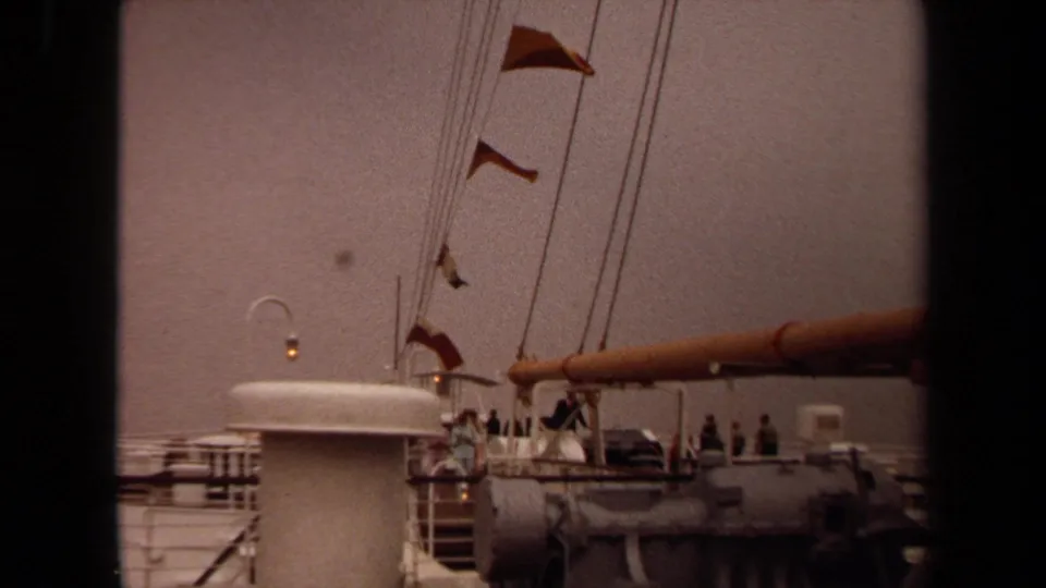 1971 Long Beach 8mm frame revealing a stationary ship deck with signal flags and background visitors.