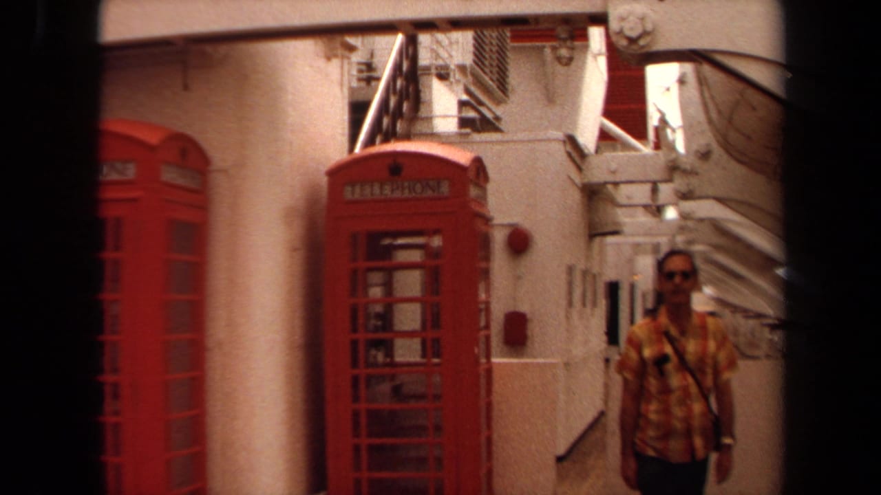 1971 Long Beach home-movie frame showing a man walking on a cruise ship deck beside red telephone booths.