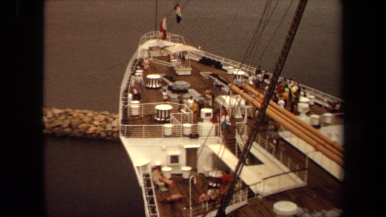 1971 Long Beach home-movie view looking down on a docked passenger ship deck with people, tables, railings, and rigging.