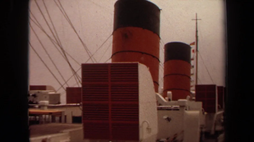Close view of a 1971 passenger ship's red vents, rigging, white structures, and red-and-black smokestacks at Long Beach.