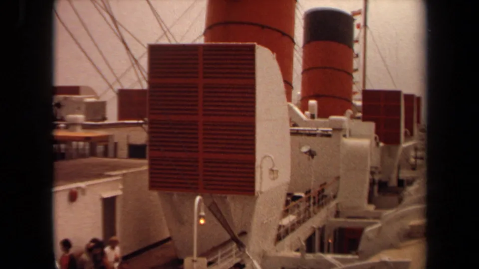 1971 Long Beach shipboard view with red vents, red-and-black smokestacks, white railings, rigging, and passengers partly visible below.