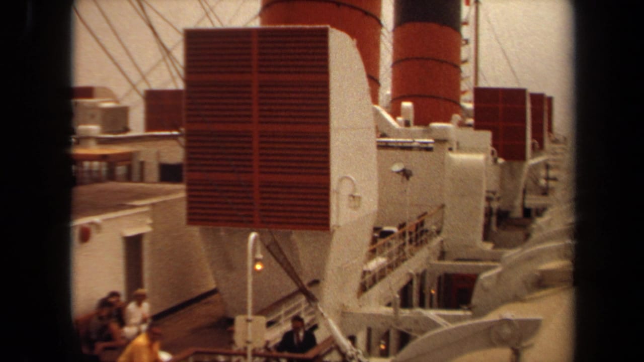 1971 Long Beach home-movie frame showing a large ship deck with red and white funnel structures, lifeboats, railings, and passengers.