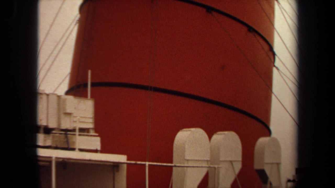 1971 Long Beach home-movie frame showing a large red ocean-liner funnel above white deck housings and railings.