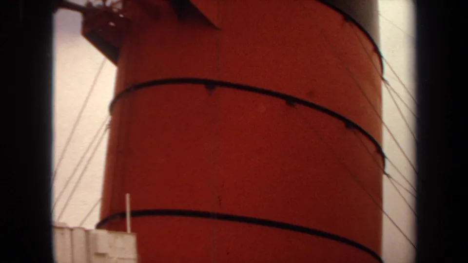 1971 maritime home-movie frame with the red funnel dominating the view, crossed by rigging cables and deck railings.