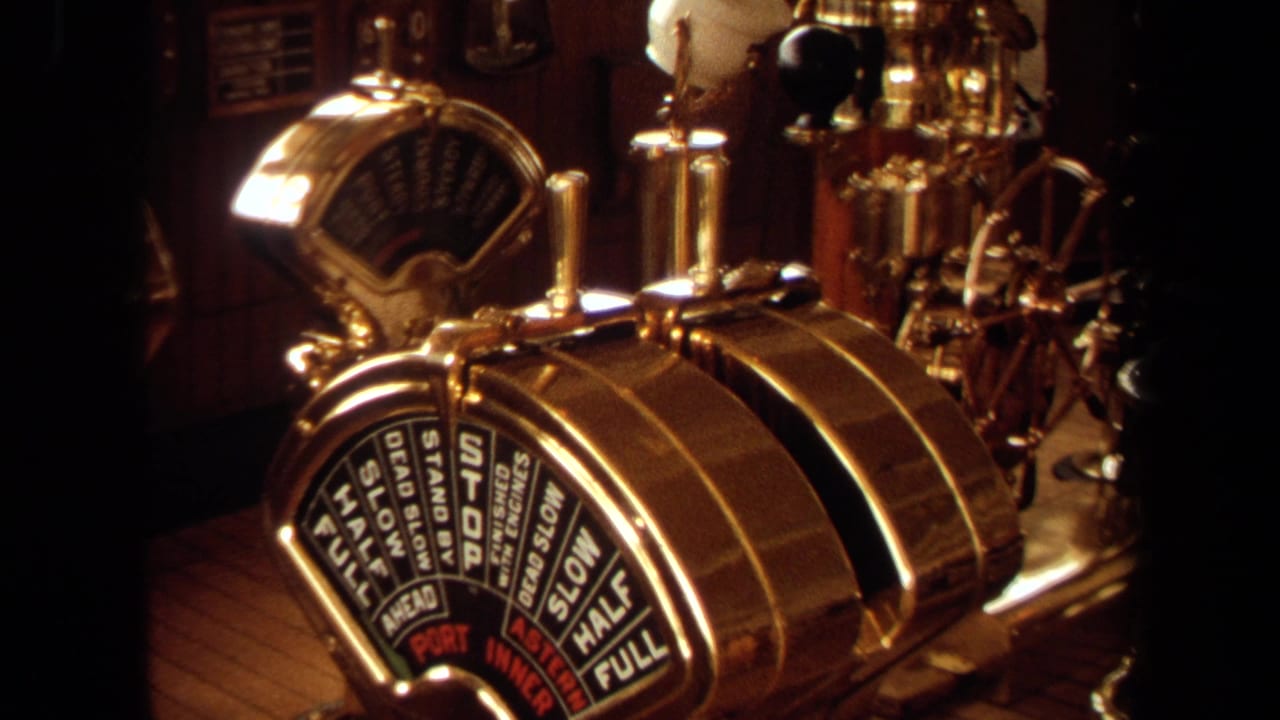 1971 Long Beach 8mm frame showing ornate brass engine-order controls with marked speed settings inside a warm wood vessel bridge.