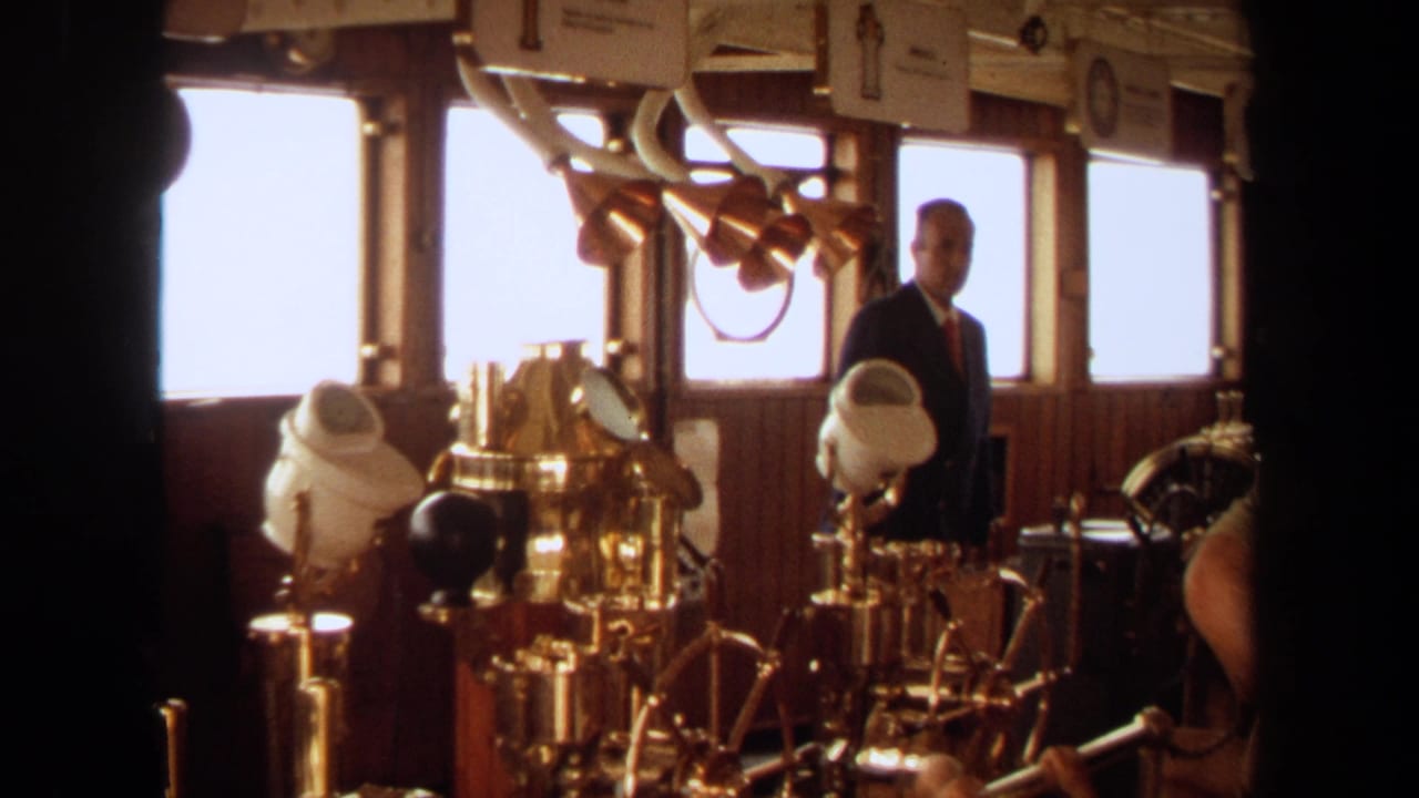 1971 Long Beach yacht bridge interior with a suited man near brass controls, windows, and wood paneling.