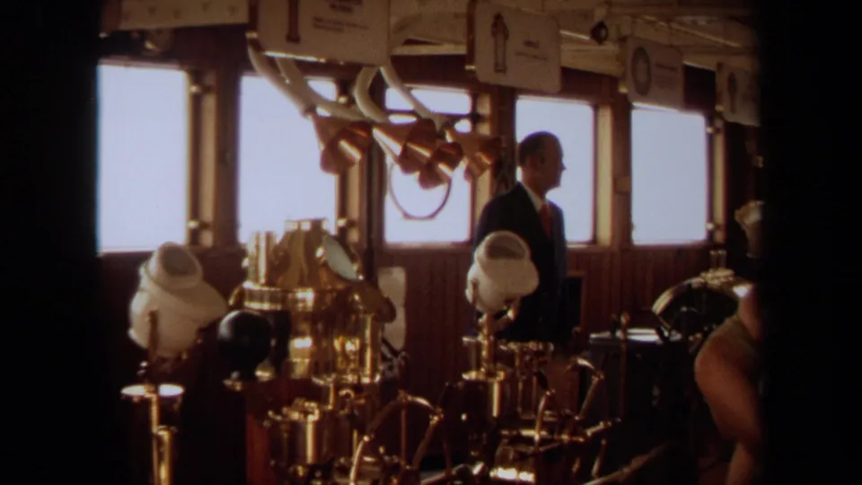1971 home-movie view of a yacht bridge in Long Beach, showing a suited man among brass controls and wood-paneled walls.