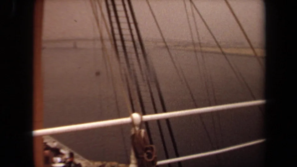 1971 8mm view of boat railing, rigging lines, and deck hardware over hazy Long Beach water.