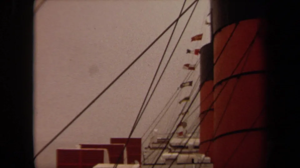 1971 Long Beach frame looking upward at rigging and small flags beside red deck structures and the edge of a large funnel.