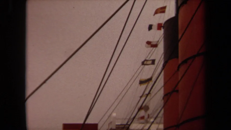 1971 Long Beach home-movie frame showing diagonal ship rigging, signal flags, and a cropped red-and-black funnel.