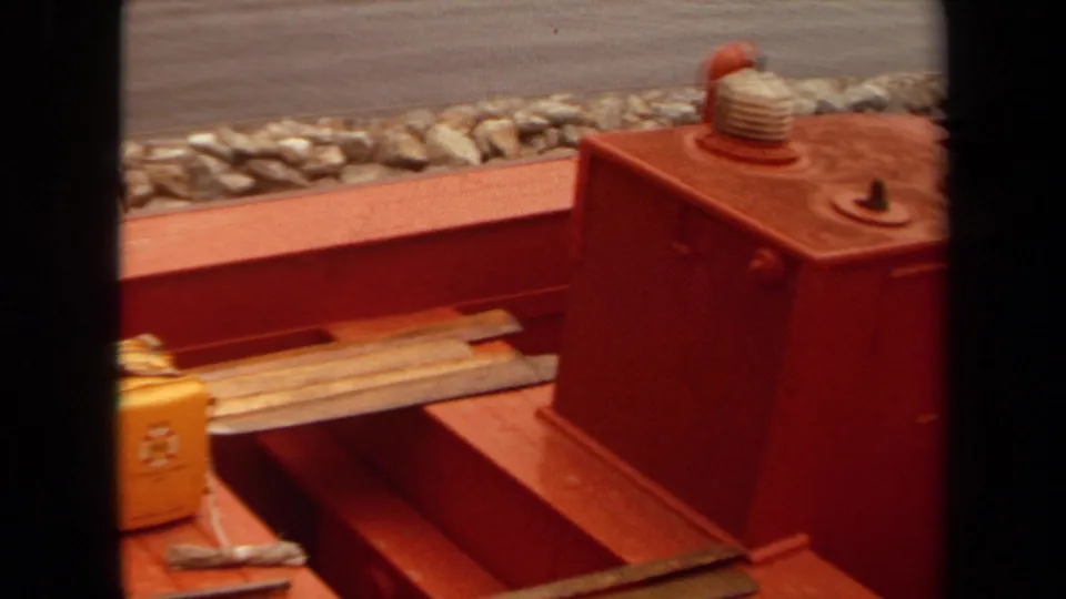 1971 Long Beach frame showing a yellow toolbox and metal rods on the red deck of a railroad maintenance vehicle.