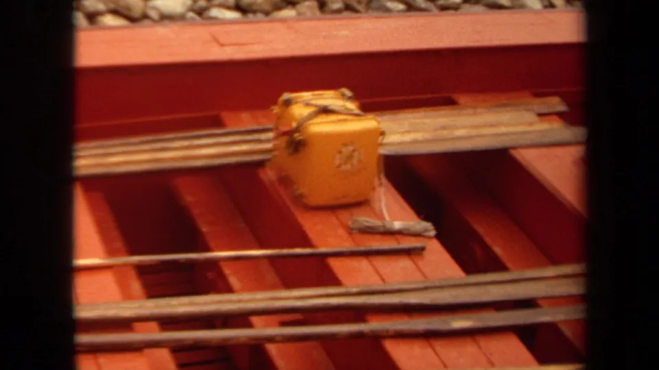 1971 Long Beach 8mm frame with a yellow toolbox, long rods, red deck openings, and gravel ballast at the edge of the work vehicle.