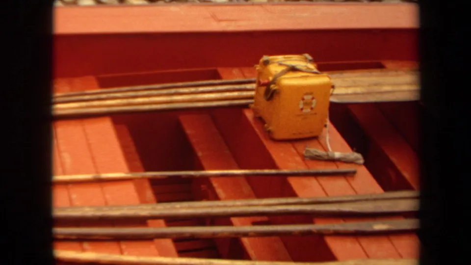 1971 Long Beach 8mm frame showing a red-painted boat interior with fishing rods, a yellow tackle box, and loose gear on deck.