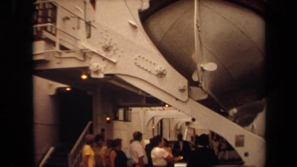 1971 Long Beach 8mm frame showing a large white ship structure, curved boat form, rivets, railings, and people gathered below.