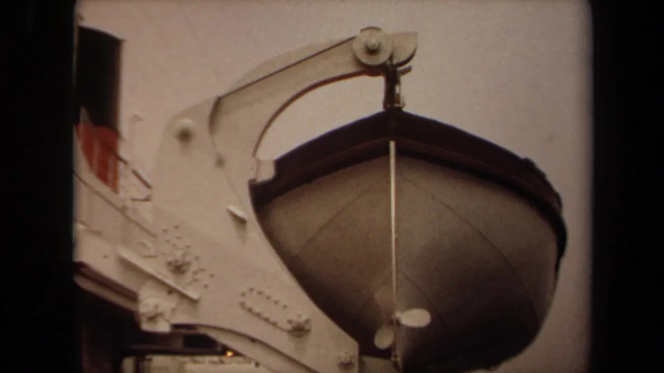 Close 1971 Long Beach 8mm view of the rounded lifeboat hull suspended beside the white ship structure.