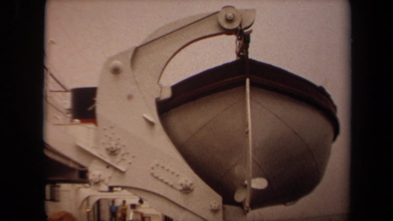 1971 Long Beach home-movie frame showing a lifeboat suspended from a white ship davit with passengers or visitors partly visible below.