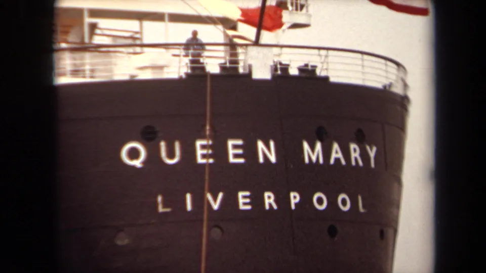 1971 Long Beach 8mm frame showing the Queen Mary bow, white Liverpool lettering, upper deck railings, and a small figure above.